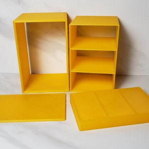May include: A set of four yellow plastic storage boxes with lids. The boxes are different sizes and can be stacked on top of each other.