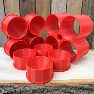 May include: A bright red plastic organizer with multiple circular compartments for storing small items. The organizer is made of 3D printed plastic and has a modern, geometric design.