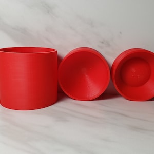 May include: Three red plastic moulds, one cylindrical and two hemispherical.