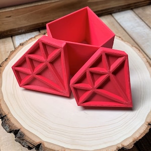 May include: A bright red diamond-shaped box with a lid. The box is made of plastic and has a smooth, glossy finish.