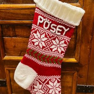 Può includere: Calza di Natale a maglia rossa e bianca con un motivo a fiocco di neve e il nome "PÖSEY" ricamato in bianco.