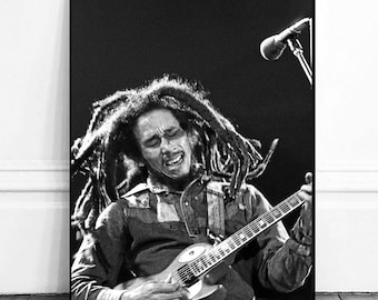 May include: Black and white photo of a musician with long dreadlocks playing a guitar. The musician is wearing a denim shirt and has a serious expression on their face.