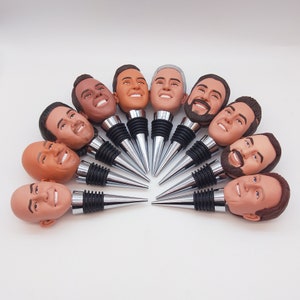 May include: A set of 10 bottle stoppers featuring different faces. Each stopper is made of a silver metal with a black base. The faces are all different and have a realistic look.