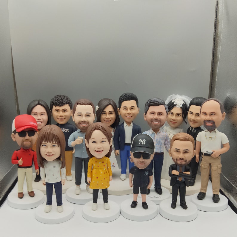 May include: A group of 14 custom-made figurines, each with unique features and clothing. The figurines are standing on a white surface and are arranged in a semi-circle.