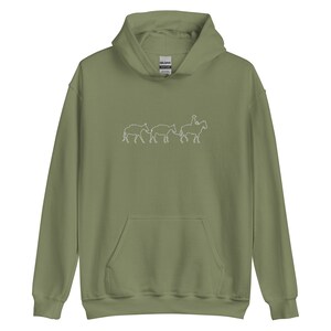 Könnte beinhalten: Ein grüner Kapuzenpullover mit einer weißen Umrandung einer Person, die auf einem Pferd reitet, und drei weiteren Pferden, die folgen.