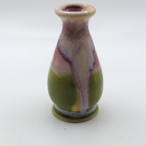 Pu&ograve; includere: Un piccolo vaso in ceramica verde e rosa con corpo rotondo e collo stretto.