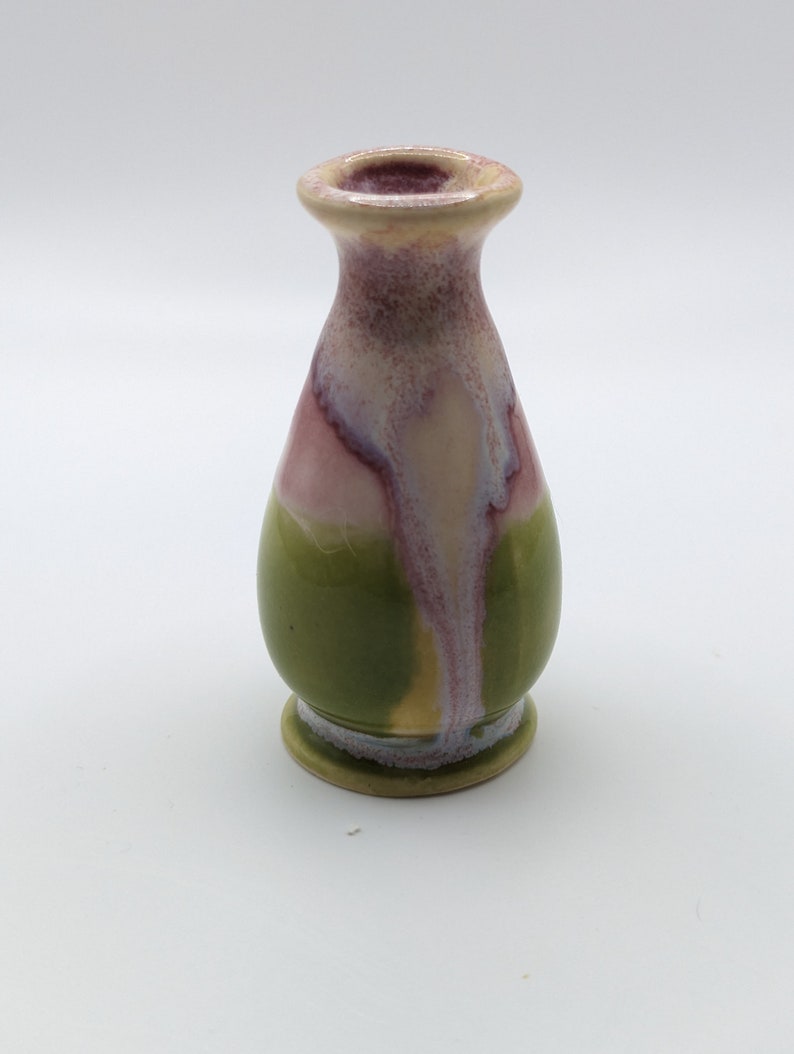 Pu&ograve; includere: Un piccolo vaso in ceramica verde e rosa con corpo rotondo e collo stretto.