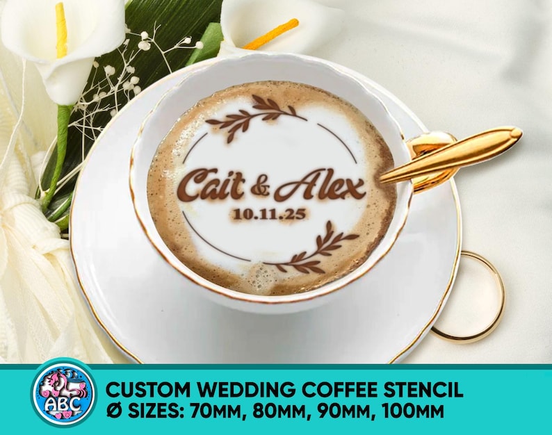 May include: A white teacup and saucer with gold trim, holding coffee art. The coffee art features the names "Cait & Alex" and the date "10.11.25" within a decorative circle. The image also includes text: "CUSTOM WEDDING COFFEE STENCIL".
