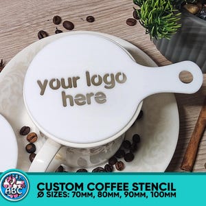 May include: White plastic coffee stencil with a handle. The stencil has the text "your logo here" printed on it. The stencil is on a white saucer with coffee beans around it. The stencil is available in sizes 70mm, 80mm, 90mm, and 100mm.