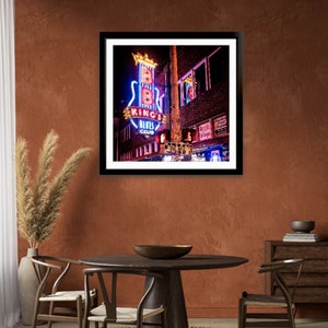 May include: A framed photograph of a neon sign for "B.B. King's Blues Club" in Memphis, Tennessee. The sign is shaped like a guitar and features the club's name in red and blue neon letters.