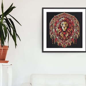 May include: A framed art print depicting a lion's head in red and gold tones, set against a black backdrop. The lion is the focal point of an elaborate, shield-shaped design. The artwork is displayed on a white wall, next to a potted plant.