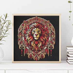 May include: Cross-stitch artwork in a wooden frame, depicting a lion's head with a red and gold mane on a black background. The design is framed in a light wood tone. The artwork is displayed on a white surface.