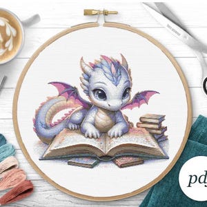 May include: A cross stitch pattern featuring a cute, white and purple dragon reading a book. The dragon has large, blue eyes and a pink, open mouth. The book is open and has a yellow spine. The dragon is sitting on a stack of books.