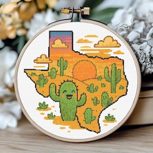 Può includere: Un telaio da ricamo a punto croce con un disegno pixelato dello stato del Texas. Il disegno comprende un cactus sorridente, cactus, un sole al tramonto e un cielo colorato nelle tonalità dell'arancione, del giallo e del blu.