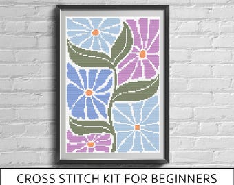 May include: A framed cross stitch pattern featuring a floral design with light blue, purple, and lavender petals, orange centers, and dark green leaves. The text below reads: CROSS STITCH KIT FOR BEGINNERS (CANVA+THREADS+PRINTED PATTERN).