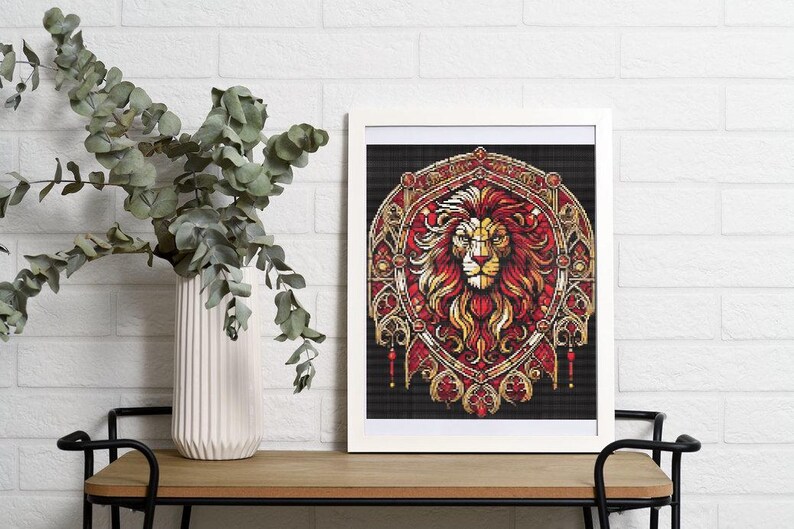 May include: A framed print depicting a lion's head with a red and gold colour scheme. The artwork has detailed patterns and is set against a black background. The print is displayed on a wooden table, alongside a white vase and greenery.