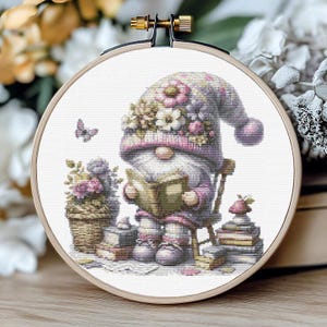 May include: A cross-stitch pattern featuring a gnome wearing a purple and pink hat with flowers, reading a book, sitting in a chair, surrounded by books and flowers.