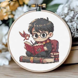 以下が含まれることがあります： 眼鏡をかけた少年が本を読んでいるクロスステッチのパターン。彼は赤と黒のローブを着ており、肩には小さな鳥がとまっている。パターンは本の山に囲まれている。