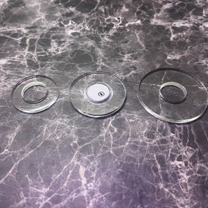 May include: Three clear glass circles of different sizes, with a smaller circle in the centre of the middle circle.