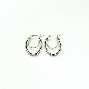 May include: Silver hoop earrings with a beaded design. The earrings are double-layered and have a simple, elegant style.
