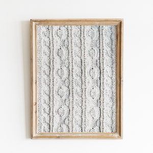 Peut inclure: Une impression encadr&eacute;e d'un motif en tricot blanc avec un cadre en bois.