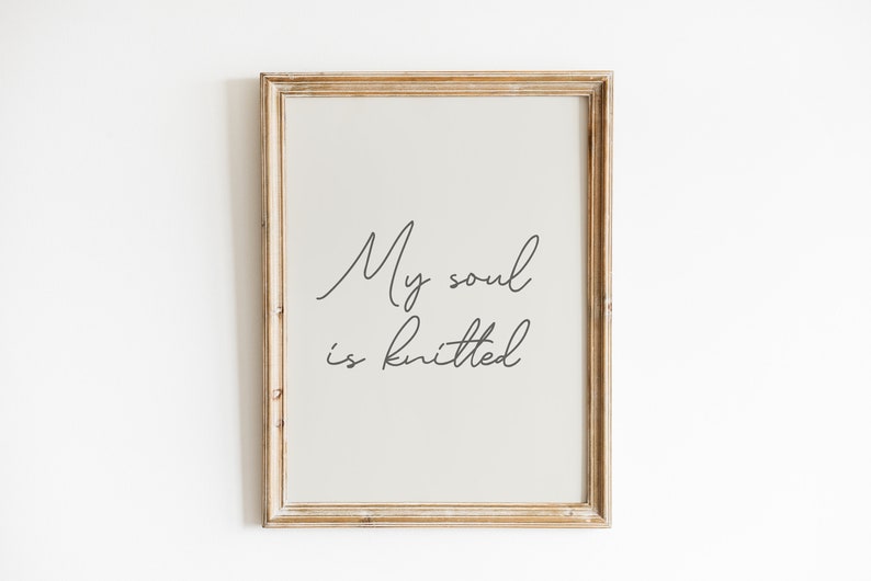 Peut inclure: Une impression encadr&eacute;e avec le texte "My soul is knitted" en &eacute;criture cursive. Le cadre est en bois clair et l'arri&egrave;re-plan est beige clair.