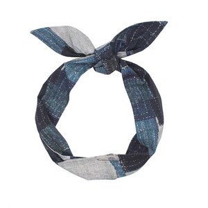 Könnte beinhalten: Ein blau-graues Stoffstirnband mit Karomuster und einem geknoteten Oberteil. Das Stirnband besteht aus einem weichen Material und weist ein sich wiederholendes Muster aus Quadraten in Blau- und Grautönen auf. Die Enden sind zu einer Schleife gebunden.