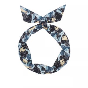 May include: A blue and white patterned headband with a design of rabbits and waves. The headband is made of fabric and is tied at the back of the head.