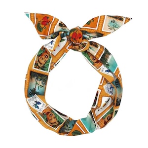 Può includere: Una fascia annodata con un motivo ripetuto di disegni di francobolli nei toni dell'arancione, del verde acqua e del bianco. I francobolli presentano immagini di persone e paesaggi. La fascia è realizzata in materiale setoso.