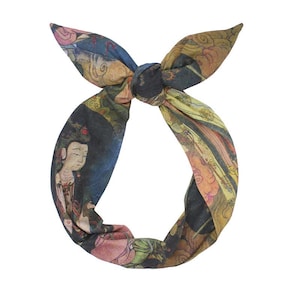 Könnte beinhalten: Ein geknotetes Stirnband mit einem farbenfrohen, künstlerischen Druck. Das Design zeigt Figuren und Muster in Blau-, Gelb-, Rosa- und Grüntönen. Das Stirnband ist oben geknotet und erzeugt einen bogenartigen Look.