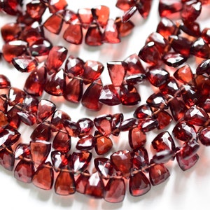 Puede incluir: Una hebra de cuentas de piedras preciosas de granate rojo oscuro, cada cuenta está facetada y tiene una forma irregular única. Las cuentas están enhebradas en un hilo transparente y están listas para ser utilizadas en la elaboración de joyas.