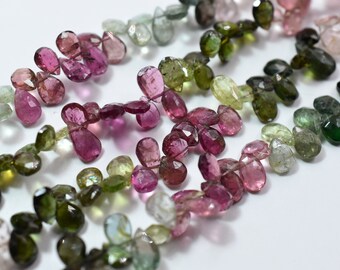 May include: A strand of faceted gemstone beads in shades of pink, green, and blue. The beads are teardrop shaped and have a polished finish.