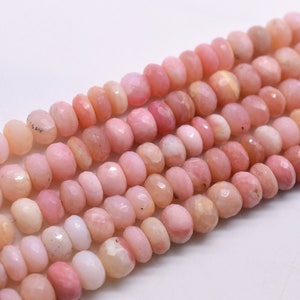 May include: A strand of pink opal beads, each bead is faceted and has a slightly irregular shape. The beads are strung together on a clear thread.