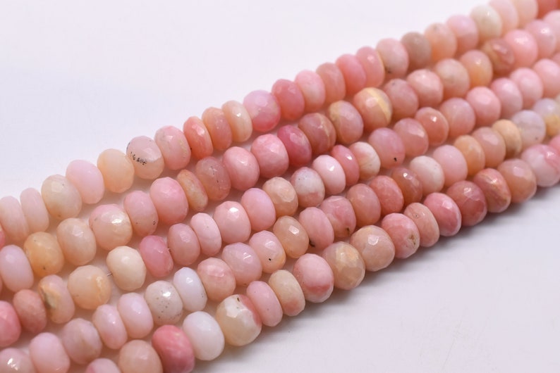 May include: A strand of pink opal beads, each bead is faceted and has a slightly irregular shape. The beads are strung together on a clear thread.