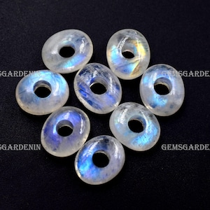 May include: Eight iridescent moonstone donut beads with a hole in the centre. The beads are a light blue colour with a white base and have a rainbow sheen.