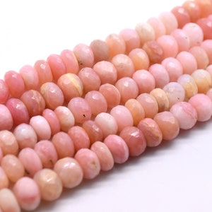 May include: A strand of pink opal beads, faceted and polished, with a slightly irregular shape. The beads are strung together on a clear thread.