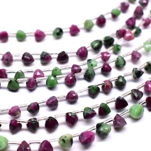 May include: A strand of green and pink gemstone beads, each bead is faceted and shaped like a triangle. The beads are strung on silver wire.