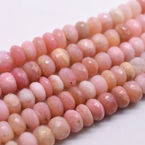 May include: A strand of pink opal beads, each bead is faceted and has a slightly irregular shape. The beads are strung together on a clear thread.