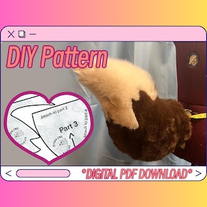 May include: A DIY pattern for a plush toy tail. The pattern is in the shape of a heart and includes instructions for attaching the tail to other parts of the toy. The text on the pattern says "Attach to part 2", "Part 3", "Attach to part 4", "Kitten Cafe", and "Studios". The image also shows a brown and white plush tail.