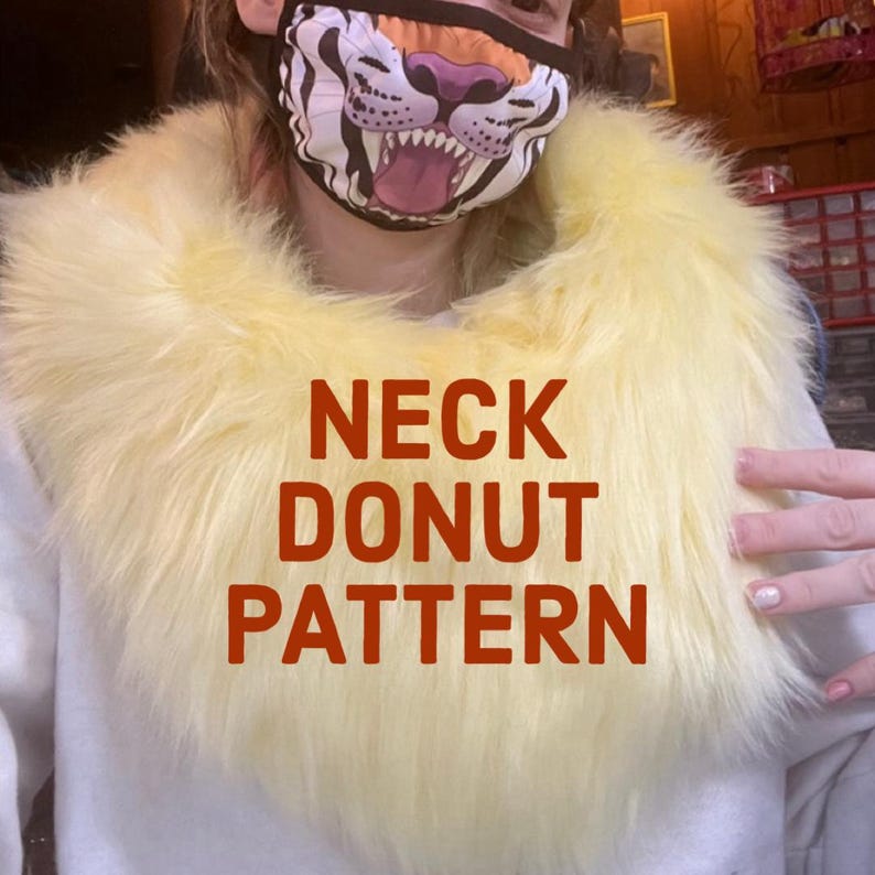 May include: A fluffy, yellow faux fur neck donut. The text "NECK DONUT PATTERN" is displayed in large, red letters across the front of the donut. The item is designed to be worn around the neck.