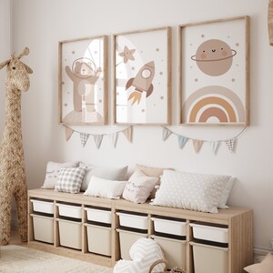 May include: A light wood bench with storage bins and three pillows. The bench is decorated with a string of flags and three framed prints with a space theme. The prints feature a bear in a spacesuit, a rocket ship, and a planet with a rainbow.