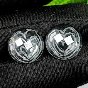 Puede incluir: Dos pendientes en forma de corazón negros y blancos con un patrón de cuadros.