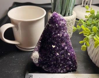 May include: A large amethyst crystal cluster with a deep purple color and a natural, rough texture. The crystal is approximately 4 inches wide and 3 inches tall.
