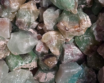 May include: A close-up of a pile of green, translucent, and opaque stones. The stones are various sizes and shapes, and some have a white or brown tint.