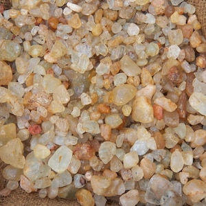 May include: A burlap sack filled with a variety of small, translucent, and semi-translucent quartz crystals. The crystals are mostly white with some having a light brown or yellow tint.