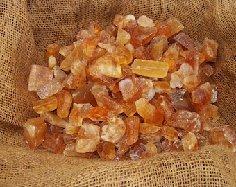 May include: A burlap sack filled with a large quantity of rough, orange-brown, translucent gemstone chips.