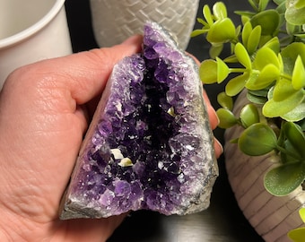 May include: A large amethyst geode with a purple crystal interior. The geode is in the shape of a heart and has a rough, natural exterior.