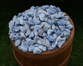 May include: A large wooden barrel filled with a collection of light blue and white rough, natural, tumbled blue calcite crystals.