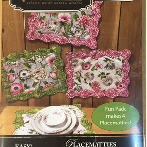 May include: Quiltsmart printed interfacing pattern for making four placemats. The pattern features a floral design with pink, green, and white colors. The text on the package reads "Fun Pack makes 4 Placematties!" and "EASY! FAST! SMART!"  "PLACEMATTIES"  "Just plain adorable!"  "Perfect for fussy-cuts and novelty prints"  "Great for fat quarters!"