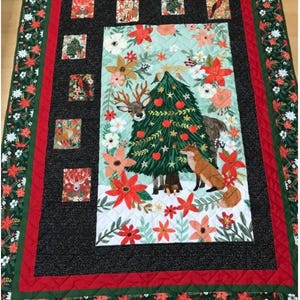 May include: A black and green quilted throw blanket with a Christmas tree and woodland animals in the center. The border is red and green with a floral pattern.